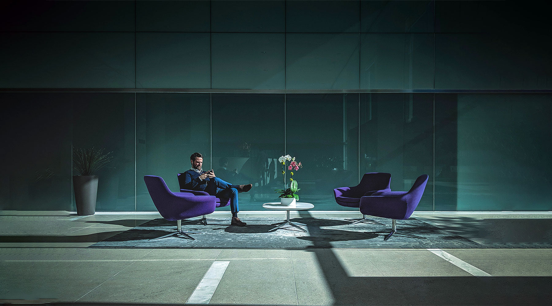 man seated in spacious lobby with purple upholstered chairs