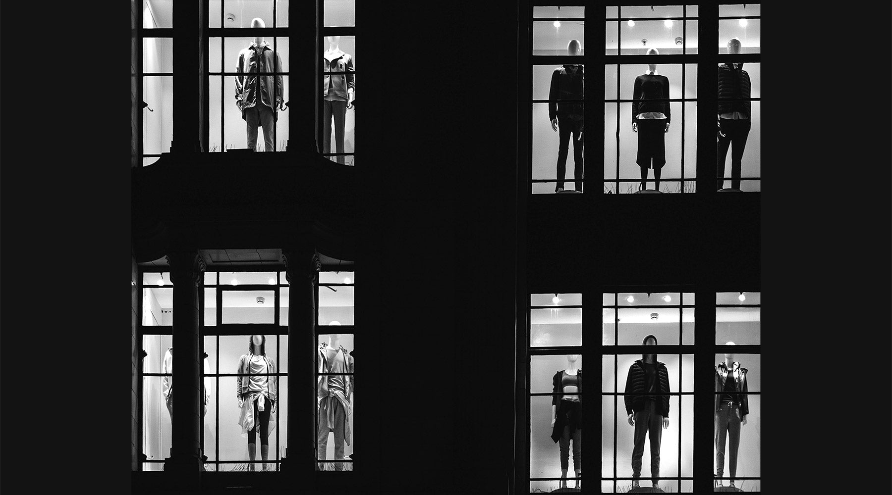 mannequins in two-story storefront windows at night