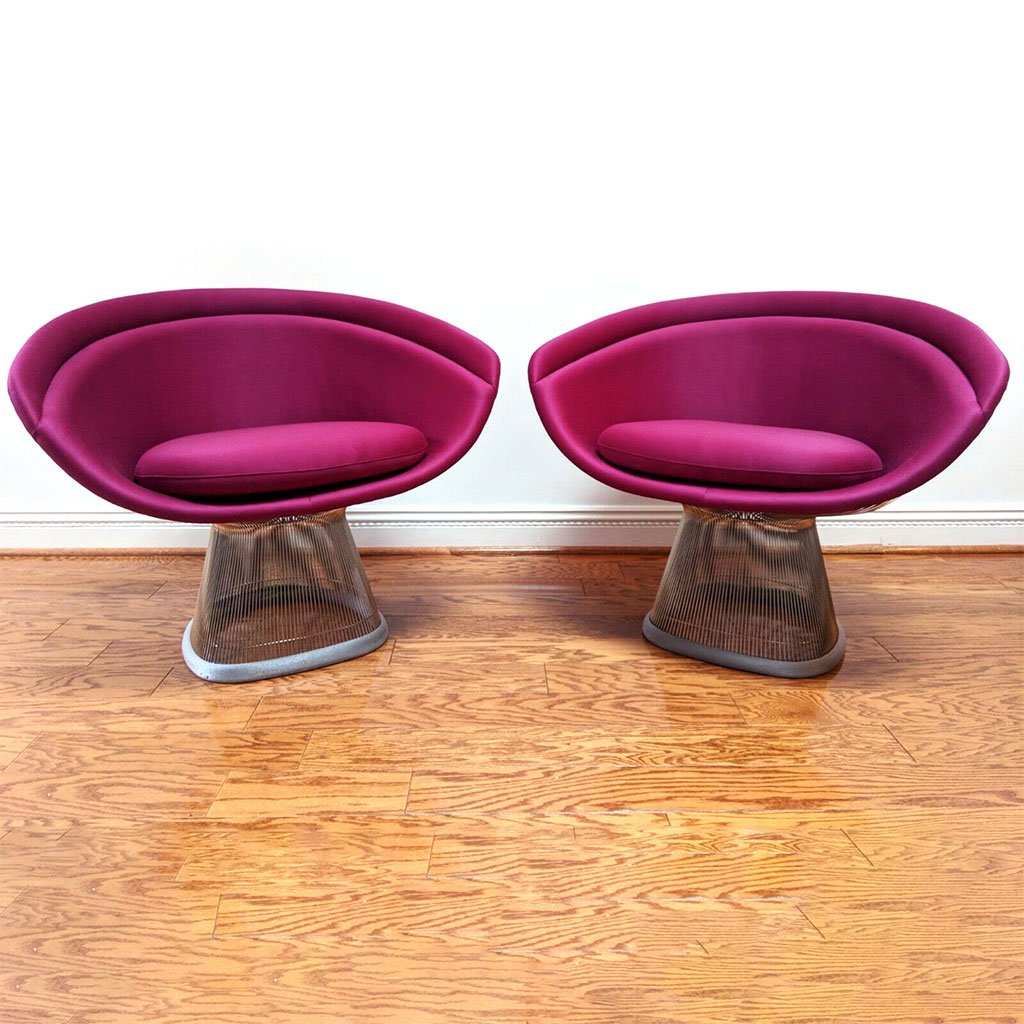 photo of a pair of colorful lounge chairs with violet cushions and backing materials, oval and supported on oval flared stand